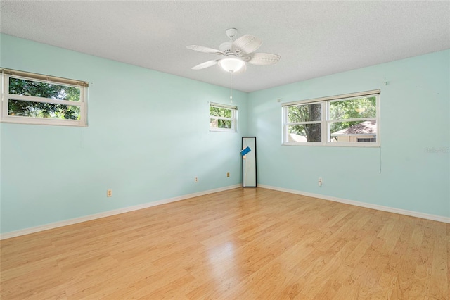 spare room with light wood-style floors, a textured ceiling, and baseboards