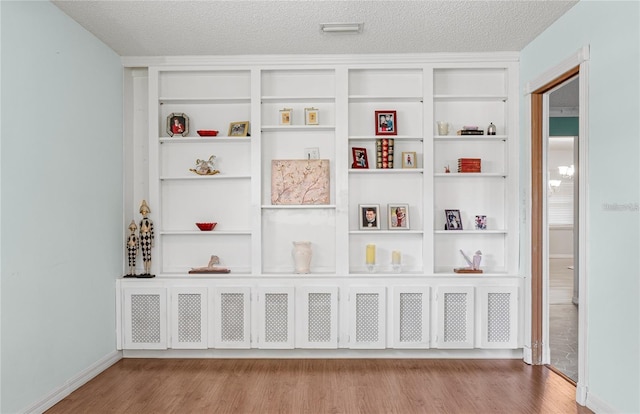 room details with built in features, baseboards, a textured ceiling, and wood finished floors