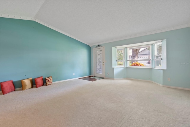 empty room featuring carpet flooring, vaulted ceiling, a textured ceiling, and baseboards