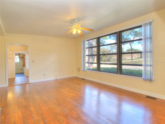 empty room with light wood-type flooring, a healthy amount of sunlight, and visible vents