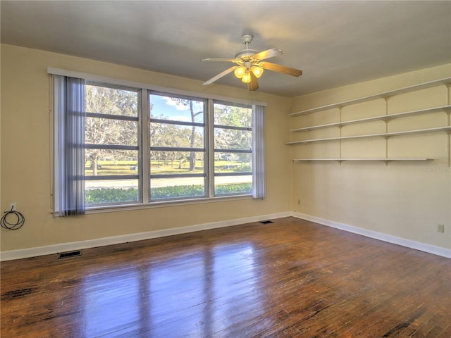 spare room with dark wood-style floors, baseboards, visible vents, and ceiling fan