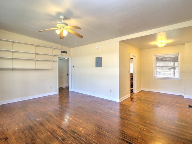 empty room featuring electric panel, baseboards, visible vents, dark wood finished floors, and a ceiling fan