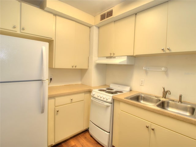 kitchen featuring white appliances, visible vents, light countertops, under cabinet range hood, and a sink