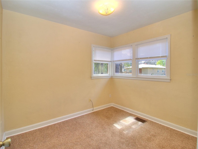 carpeted empty room with visible vents and baseboards