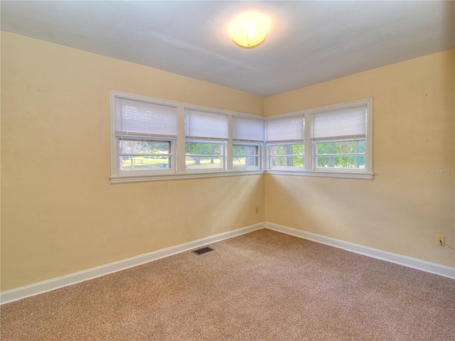 spare room featuring carpet, baseboards, and visible vents