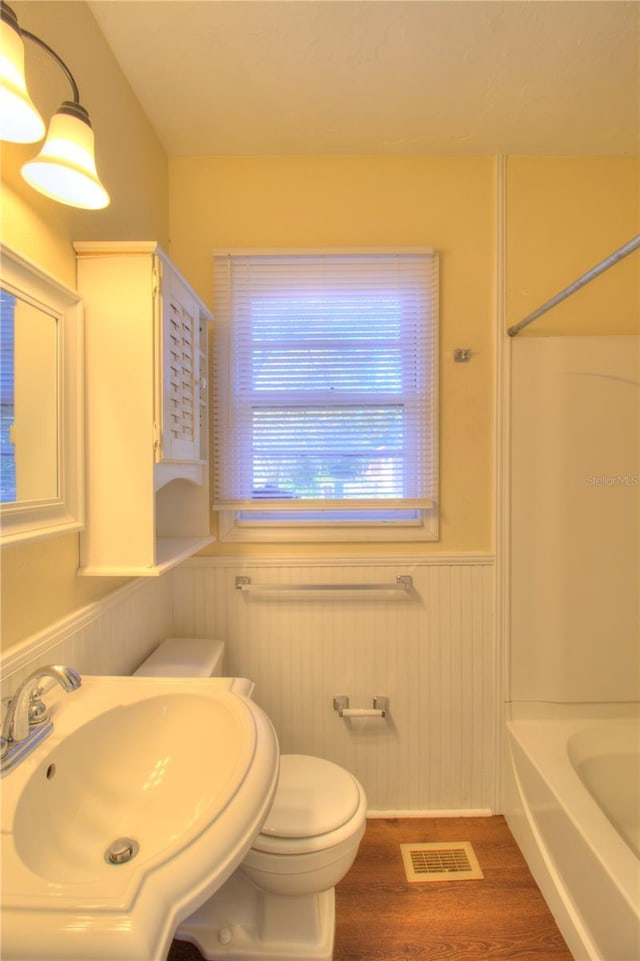 full bath featuring visible vents, toilet, wainscoting, a sink, and wood finished floors