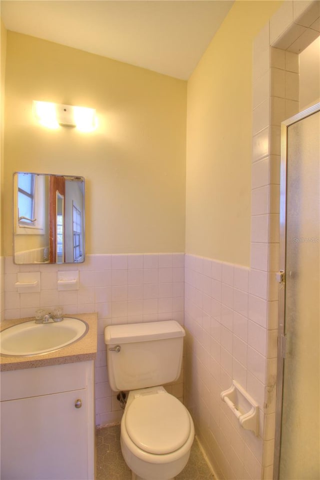 bathroom with a wainscoted wall, tile walls, toilet, and vanity