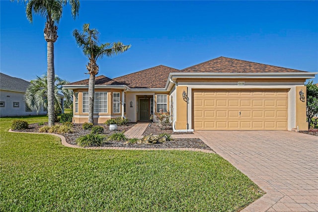 ranch-style house featuring an attached garage, a shingled roof, decorative driveway, stucco siding, and a front lawn