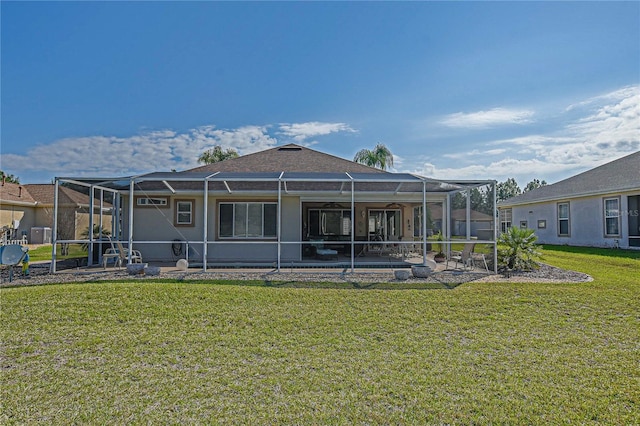 back of property with a patio area, glass enclosure, and a yard