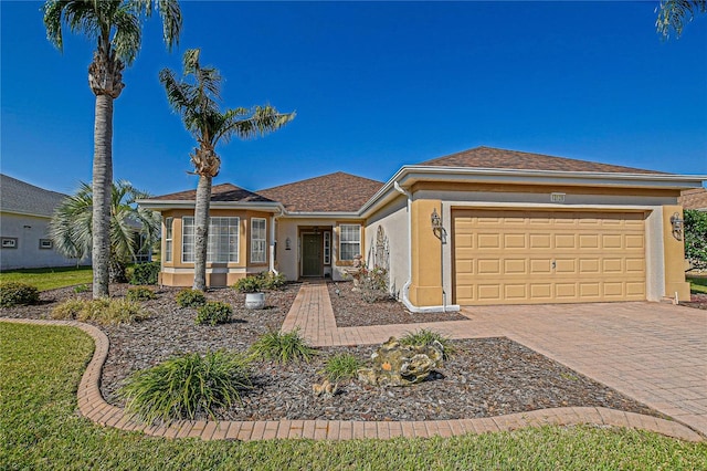 single story home featuring an attached garage, decorative driveway, and stucco siding