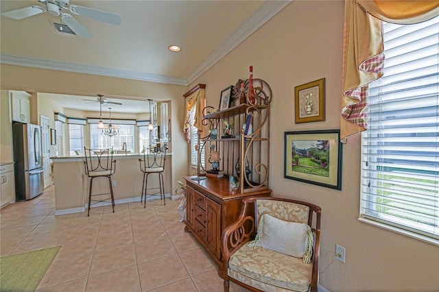 interior space with light tile patterned flooring, crown molding, baseboards, and ceiling fan with notable chandelier