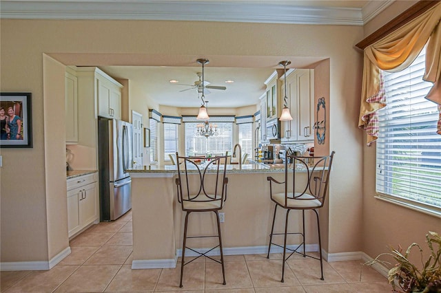 kitchen featuring light tile patterned floors, appliances with stainless steel finishes, a kitchen breakfast bar, light stone counters, and a peninsula