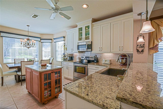 kitchen with visible vents, decorative backsplash, light stone counters, stainless steel appliances, and a sink