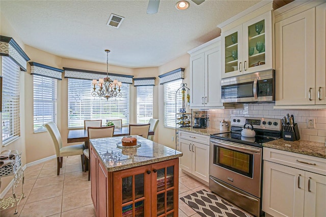 kitchen featuring light tile patterned floors, stainless steel appliances, tasteful backsplash, and visible vents