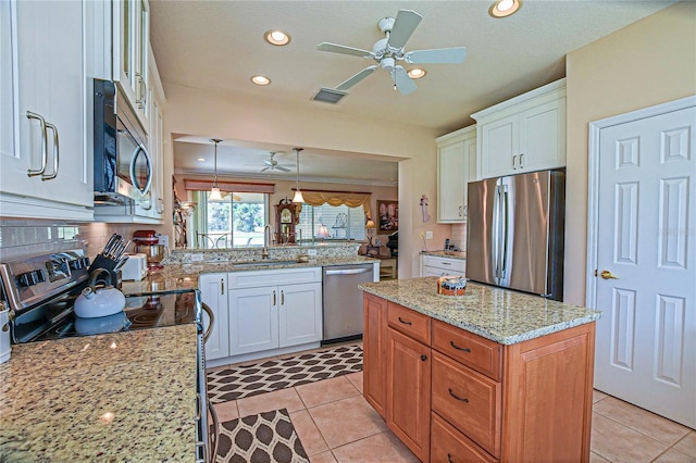 kitchen featuring light stone counters, stainless steel appliances, a peninsula, a sink, and a center island