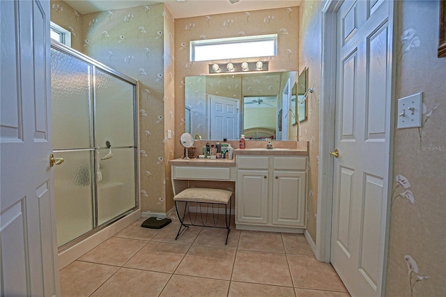 bathroom featuring tile patterned flooring, vanity, baseboards, a shower stall, and wallpapered walls