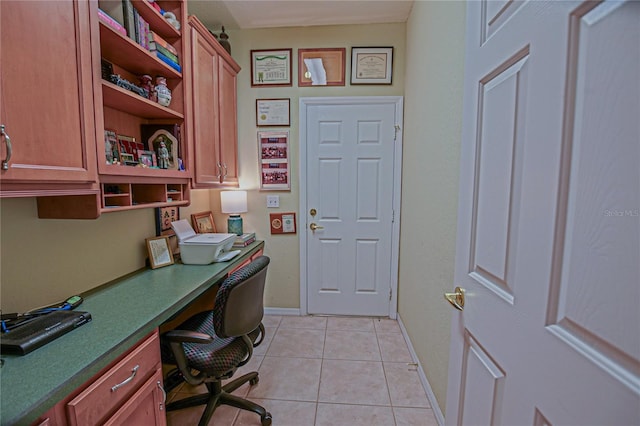 office space featuring light tile patterned floors, baseboards, and built in study area