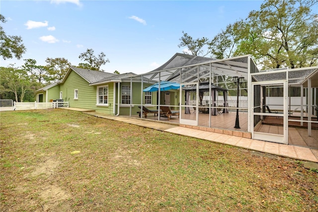 back of house featuring a pool, glass enclosure, a patio, and a lawn