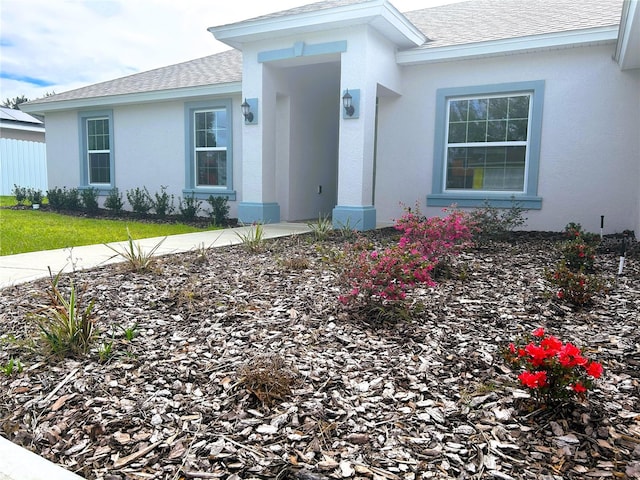 property entrance with roof with shingles and stucco siding