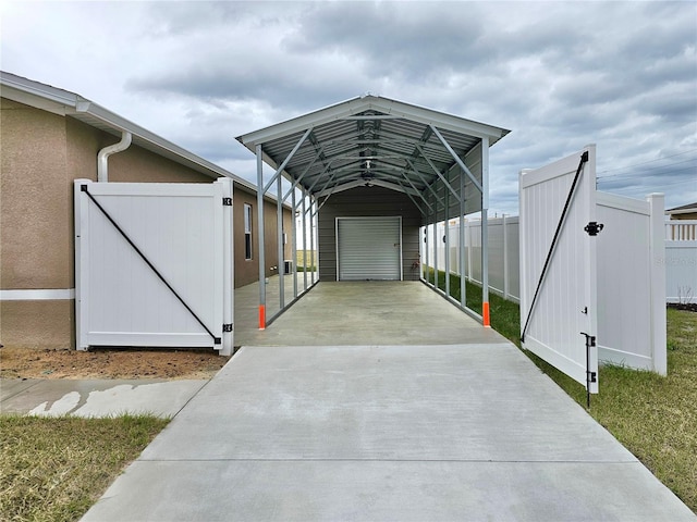 view of parking / parking lot featuring concrete driveway, fence, and a gate