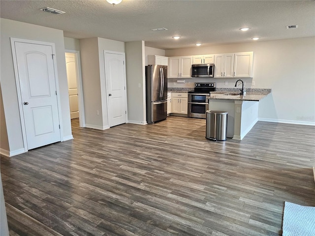 kitchen featuring stainless steel appliances, visible vents, white cabinets, a sink, and a peninsula