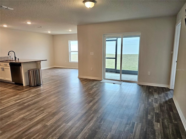 unfurnished living room with dark wood finished floors, visible vents, a sink, a textured ceiling, and baseboards