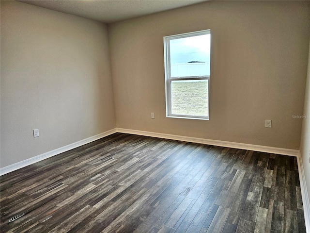 unfurnished room with dark wood-style flooring and baseboards