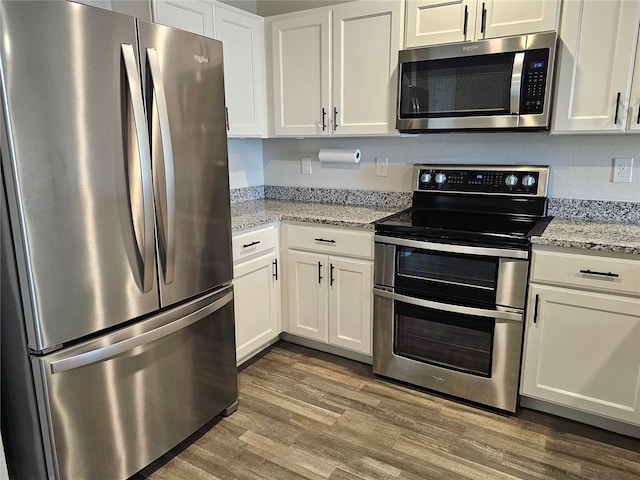 kitchen featuring appliances with stainless steel finishes, light stone counters, and white cabinets