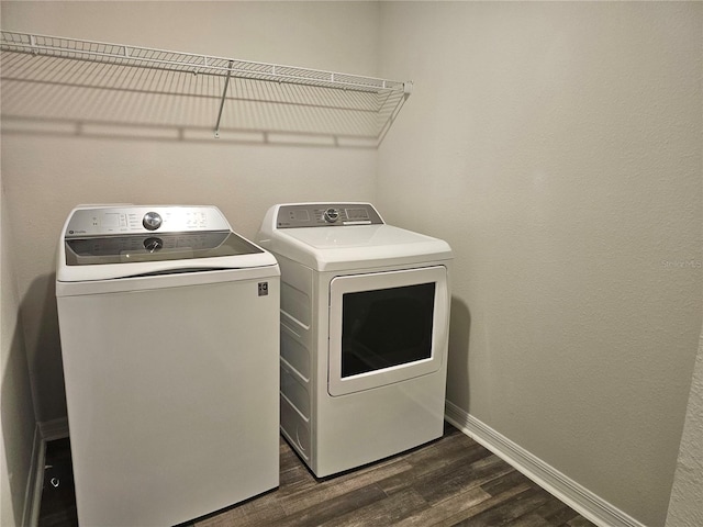 laundry area with laundry area, separate washer and dryer, dark wood finished floors, and baseboards