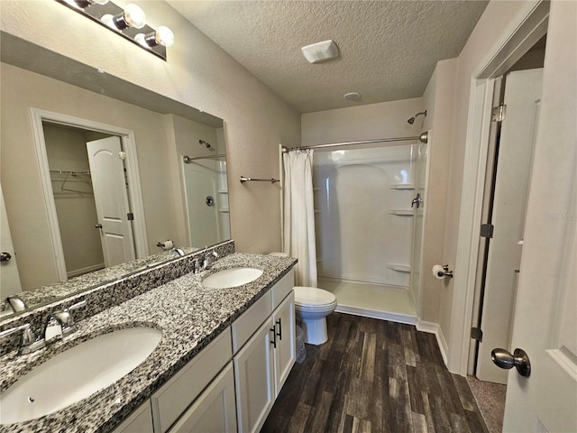 full bathroom with a textured ceiling, wood finished floors, a sink, and a shower with curtain