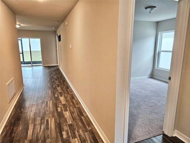 corridor featuring visible vents, dark wood finished floors, and a textured ceiling