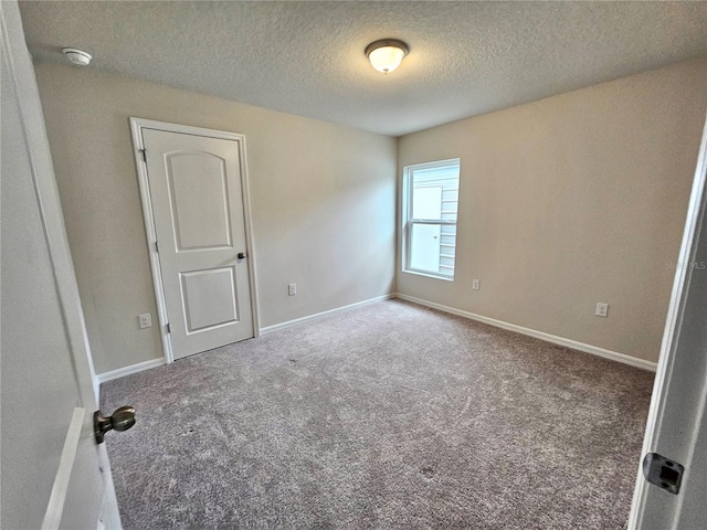 empty room featuring carpet floors, baseboards, and a textured ceiling