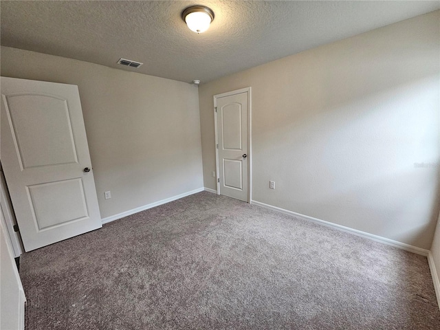 unfurnished room with baseboards, visible vents, dark colored carpet, and a textured ceiling