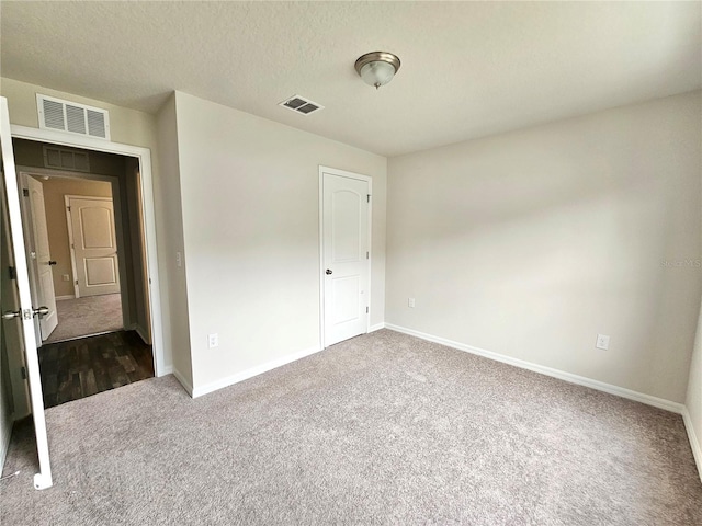 unfurnished bedroom with carpet, a textured ceiling, visible vents, and baseboards