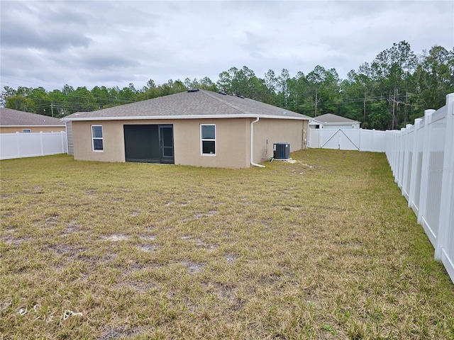 back of house with a lawn, stucco siding, a fenced backyard, and central air condition unit