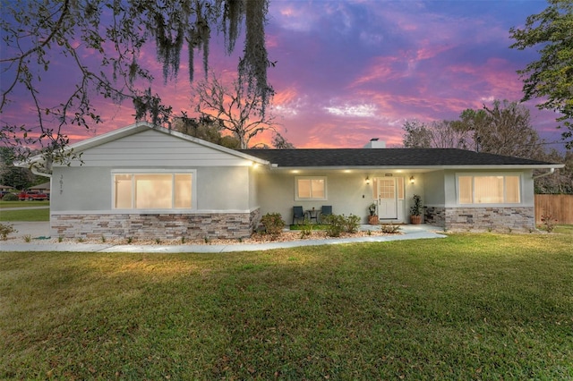 ranch-style house with stone siding, a yard, and stucco siding