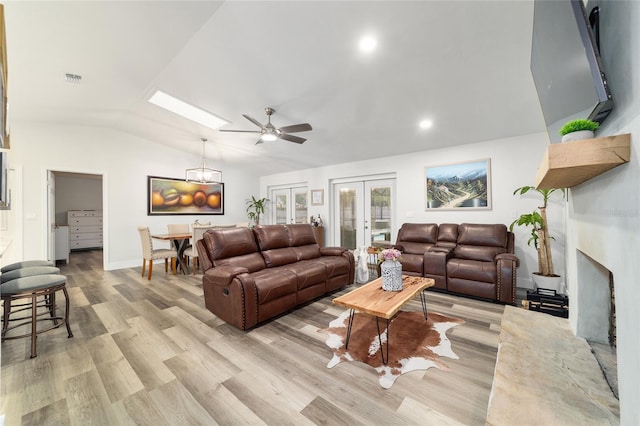 living area featuring visible vents, baseboards, french doors, light wood-type flooring, and lofted ceiling with skylight