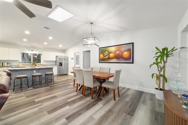 dining space featuring light wood finished floors, vaulted ceiling with skylight, visible vents, and recessed lighting