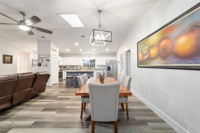 dining space featuring light wood finished floors, visible vents, baseboards, vaulted ceiling, and recessed lighting