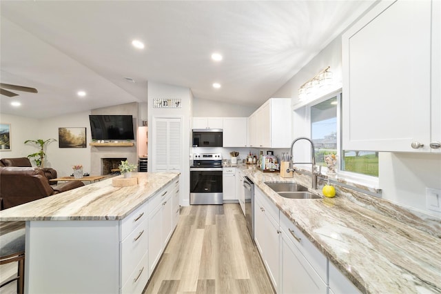 kitchen featuring white cabinets, light stone counters, stainless steel appliances, and open floor plan