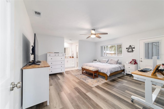 bedroom featuring ensuite bath, visible vents, and wood finished floors