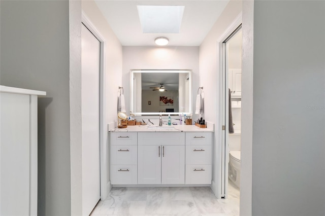 bathroom featuring toilet, marble finish floor, a skylight, and vanity