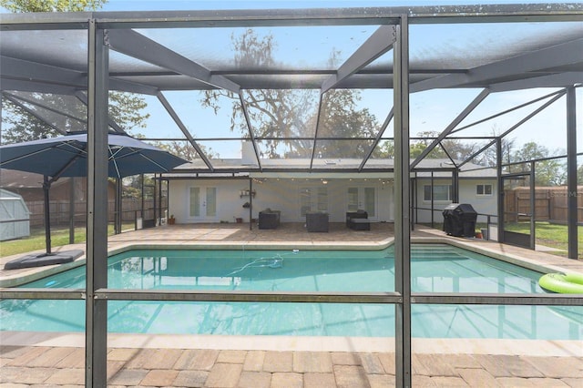 view of swimming pool with glass enclosure, fence, area for grilling, and a patio