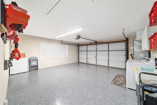 garage featuring a garage door opener, concrete block wall, refrigerator, and washer and clothes dryer