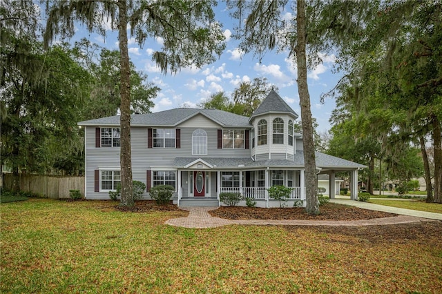 victorian house featuring driveway, fence, a front lawn, a porch, and a carport