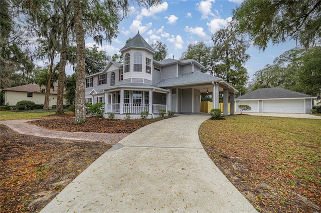 view of front facade featuring covered porch, a shingled roof, an outdoor structure, driveway, and a front yard