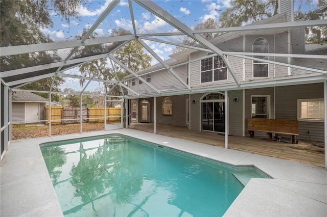 view of swimming pool with a fenced in pool, fence, a wooden deck, and a shed