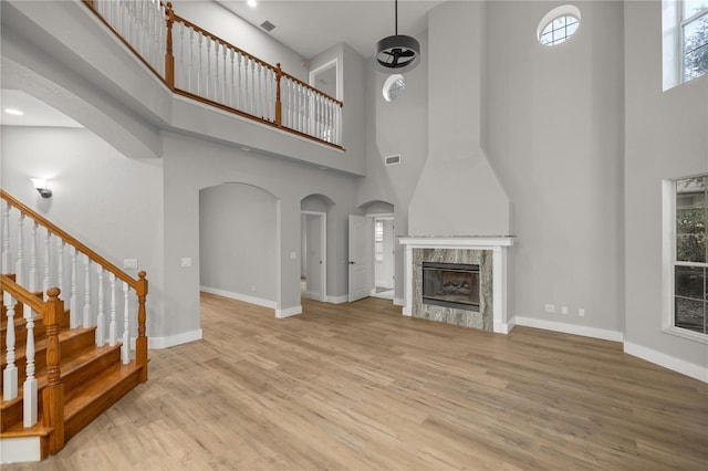 living room featuring light wood-style floors, a premium fireplace, and arched walkways