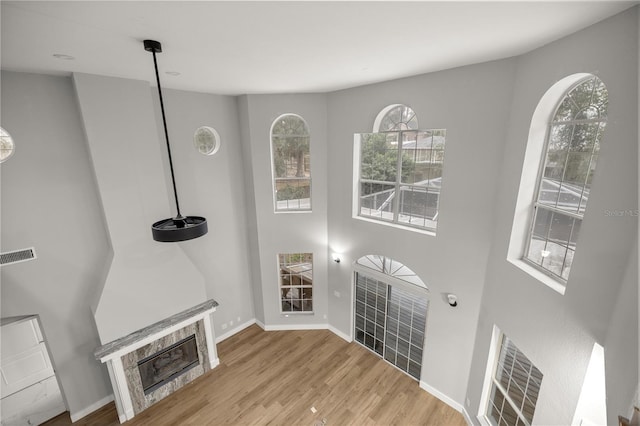 unfurnished living room featuring light wood-type flooring, baseboards, visible vents, and a tile fireplace