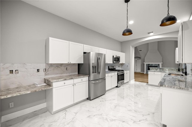 kitchen featuring appliances with stainless steel finishes, white cabinetry, a sink, and hanging light fixtures